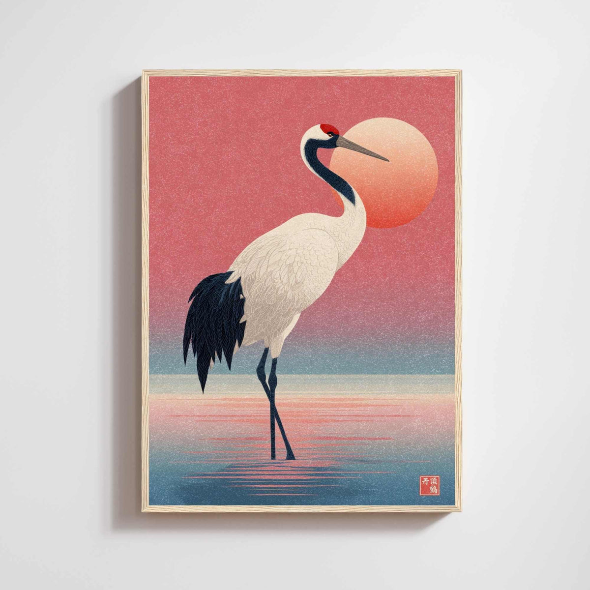 Affiche grue japonaise debout dans l’eau devant un soleil corail et un ciel rose, encadrée en bois clair