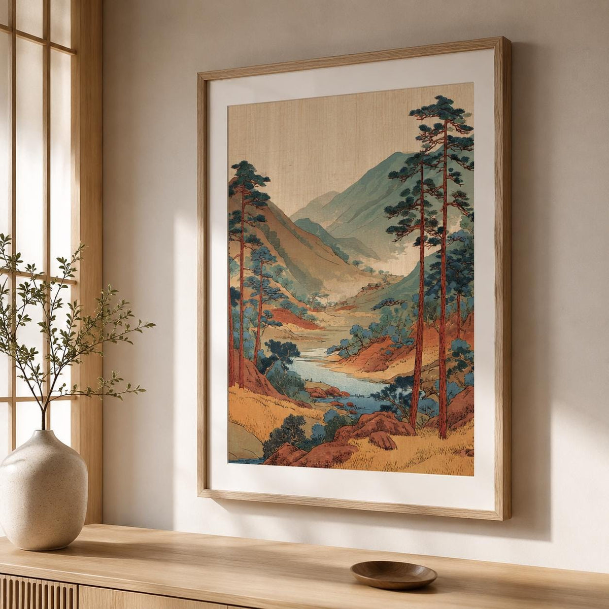 Affiche paysage japonais encadrée en bois sombre sur un mur beige, montagnes bleutées dans la brume et versants d'automne.