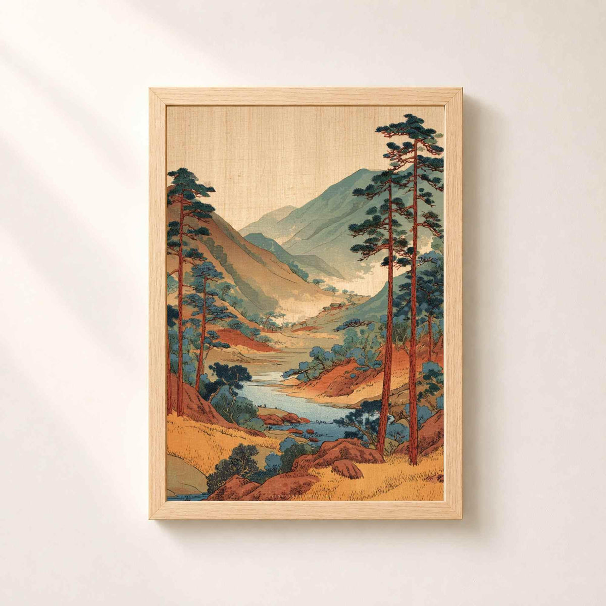 Affiche paysage japonais dans un cadre en chêne naturel sur un mur clair, vallée boisée et rivière encadrées de grands pins rouges.