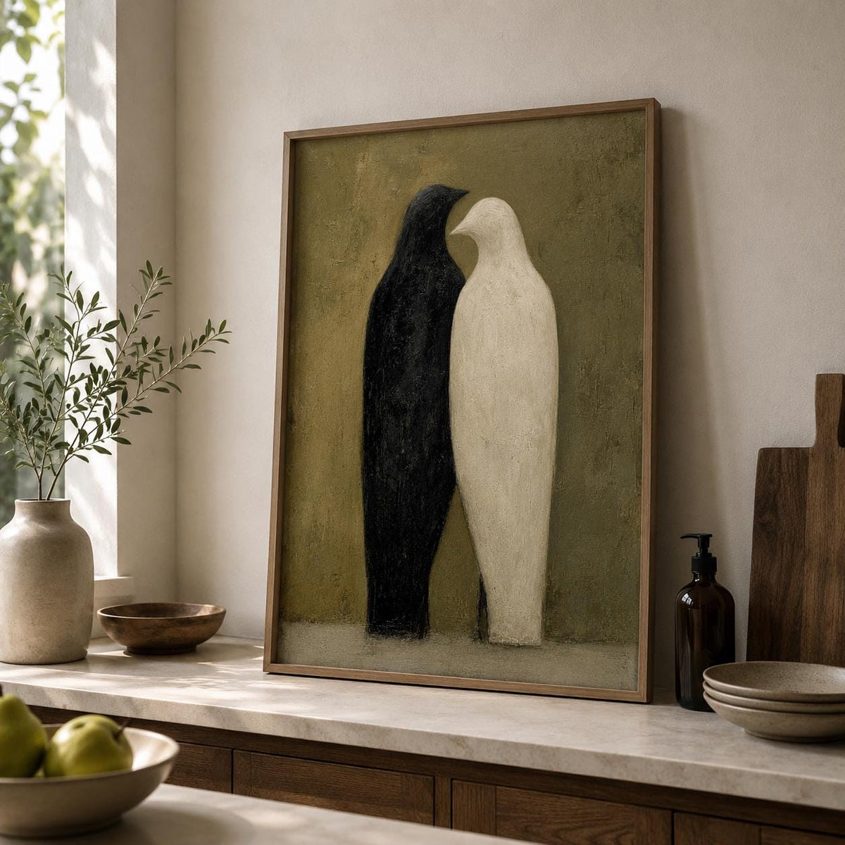 Affiche deux oiseaux dans un cadre en bois sombre sur un mur clair, un oiseau noir et un oiseau blanc stylisés côte à côte sur fond vert olive.