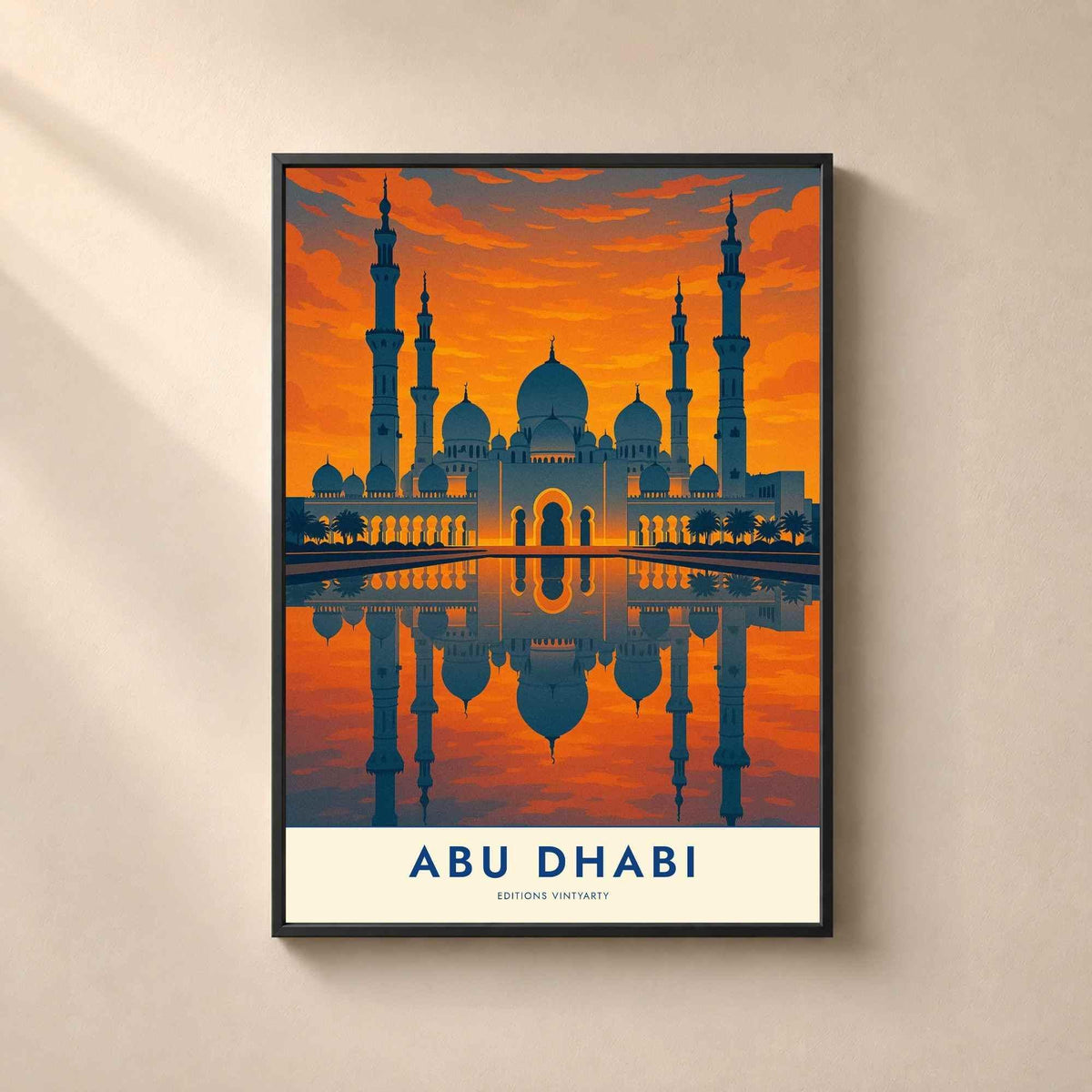 Affiche Abu Dhabi encadrée en métal noir fin sur un mur beige, grande mosquée au coucher du soleil reflétée dans un bassin.