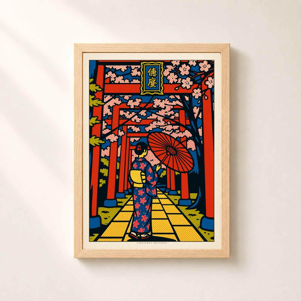 Affiche Japon dans un cadre en chêne naturel sur un mur clair, portiques rouges en perspective et branches de sakura roses.