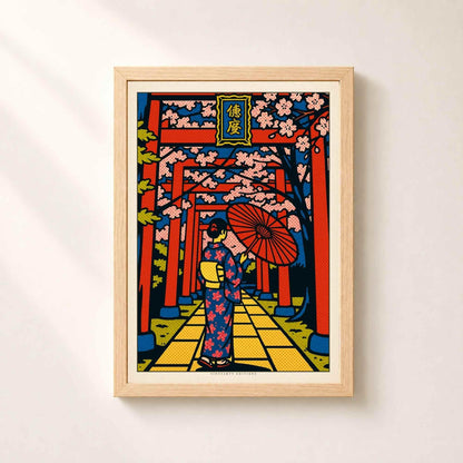 Affiche Japon dans un cadre en chêne naturel sur un mur clair, portiques rouges en perspective et branches de sakura roses.