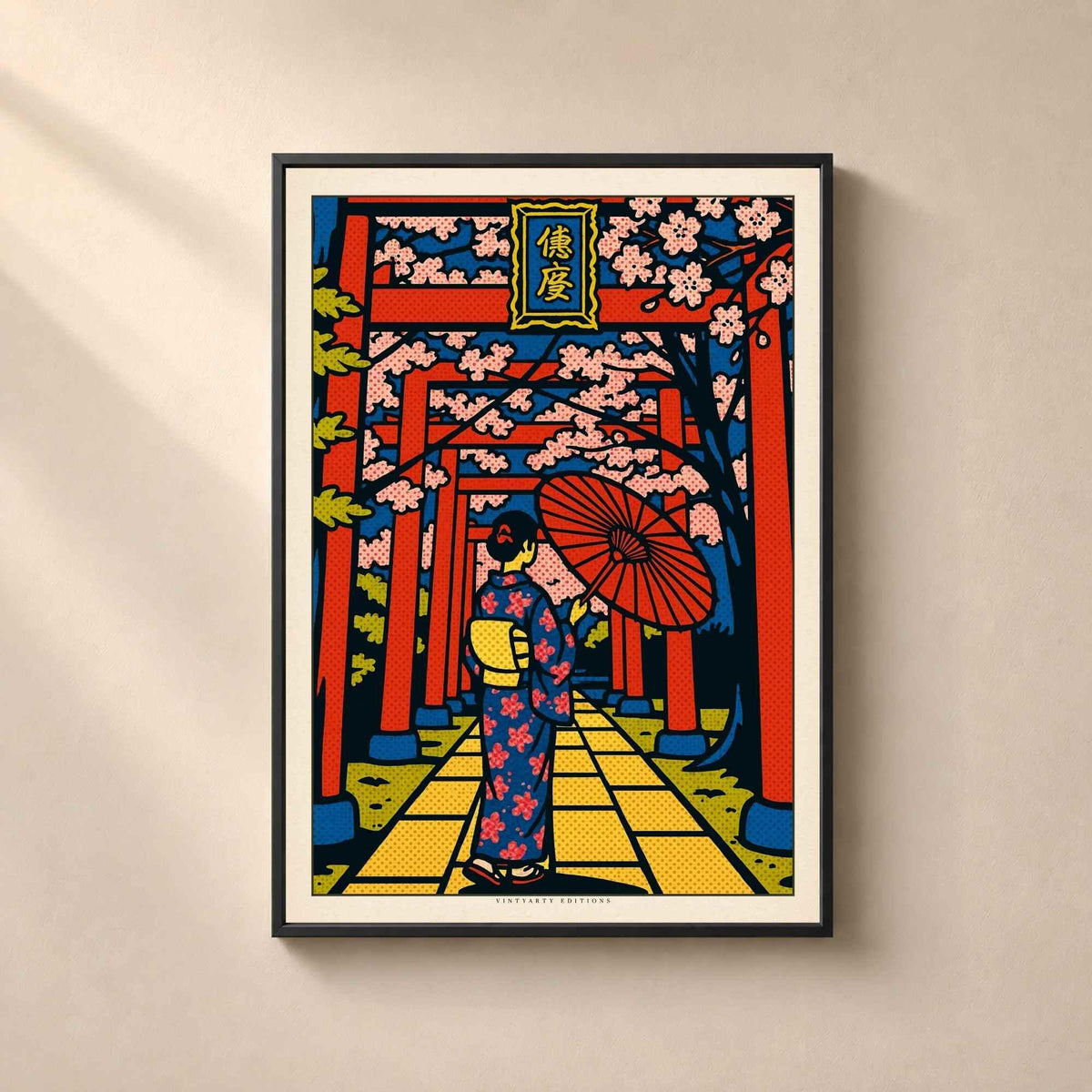 Affiche Japon encadrée en métal noir fin sur un mur beige, allée de torii rouges sous les cerisiers avec une femme en kimono et ombrelle rouge.