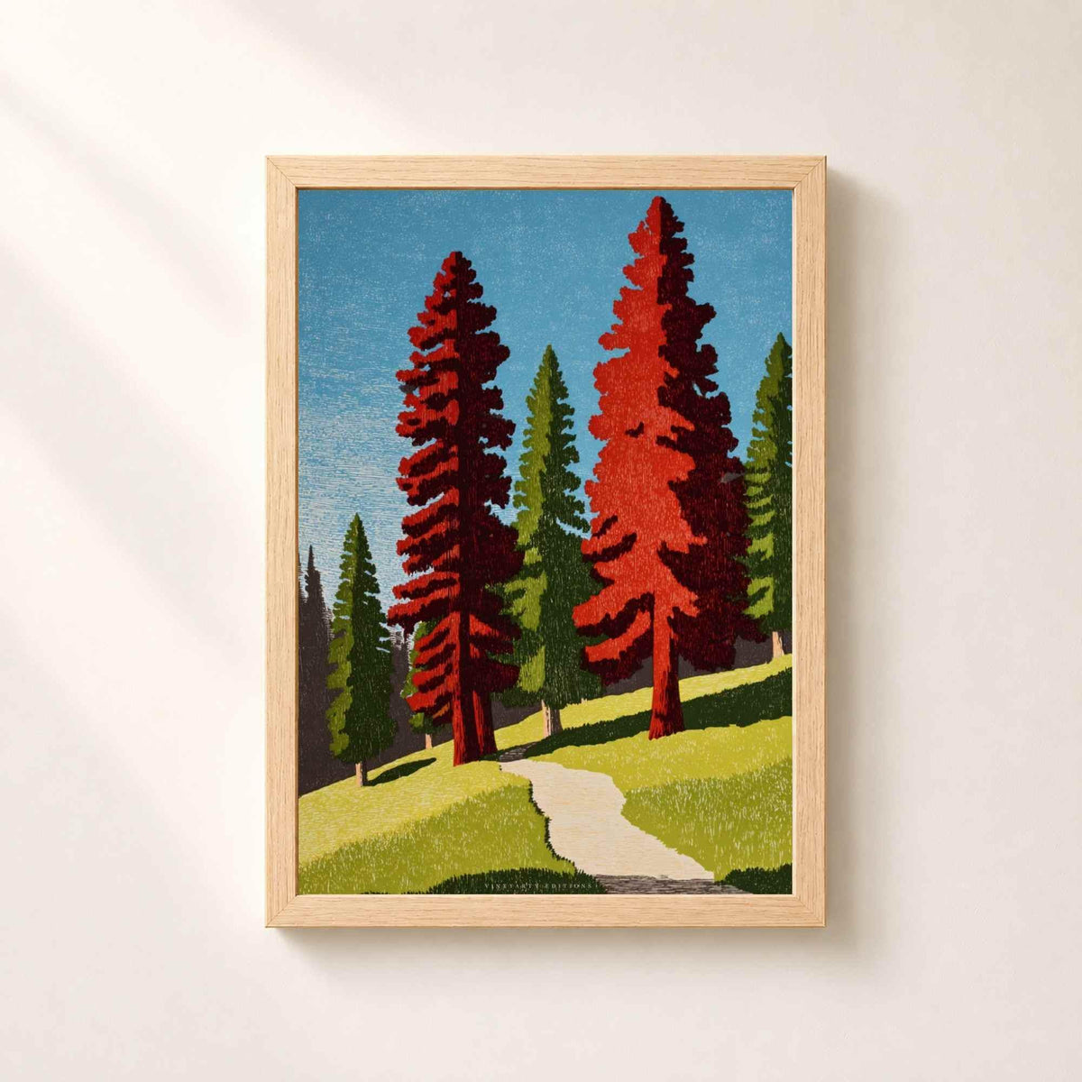 Affiche forêt de séquoias dans un cadre en chêne naturel sur un mur clair, sentier de sable montant entre deux grands arbres rouges sur une prairie verte.