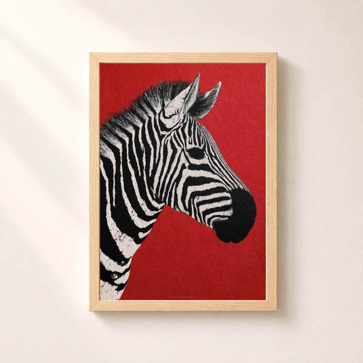 Affiche zèbre dans un cadre en chêne naturel sur un mur clair, portrait d'un zèbre noir et blanc de profil sur fond rouge vif.
