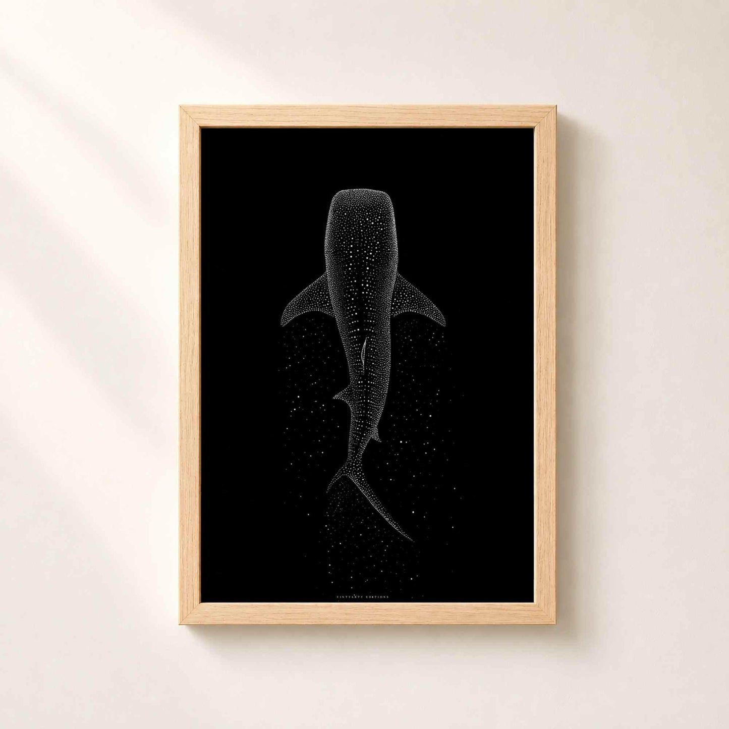 Affiche requin baleine dans un cadre en chêne naturel sur un mur clair, taches du requin dessinées en points blancs suspendus dans le noir.
