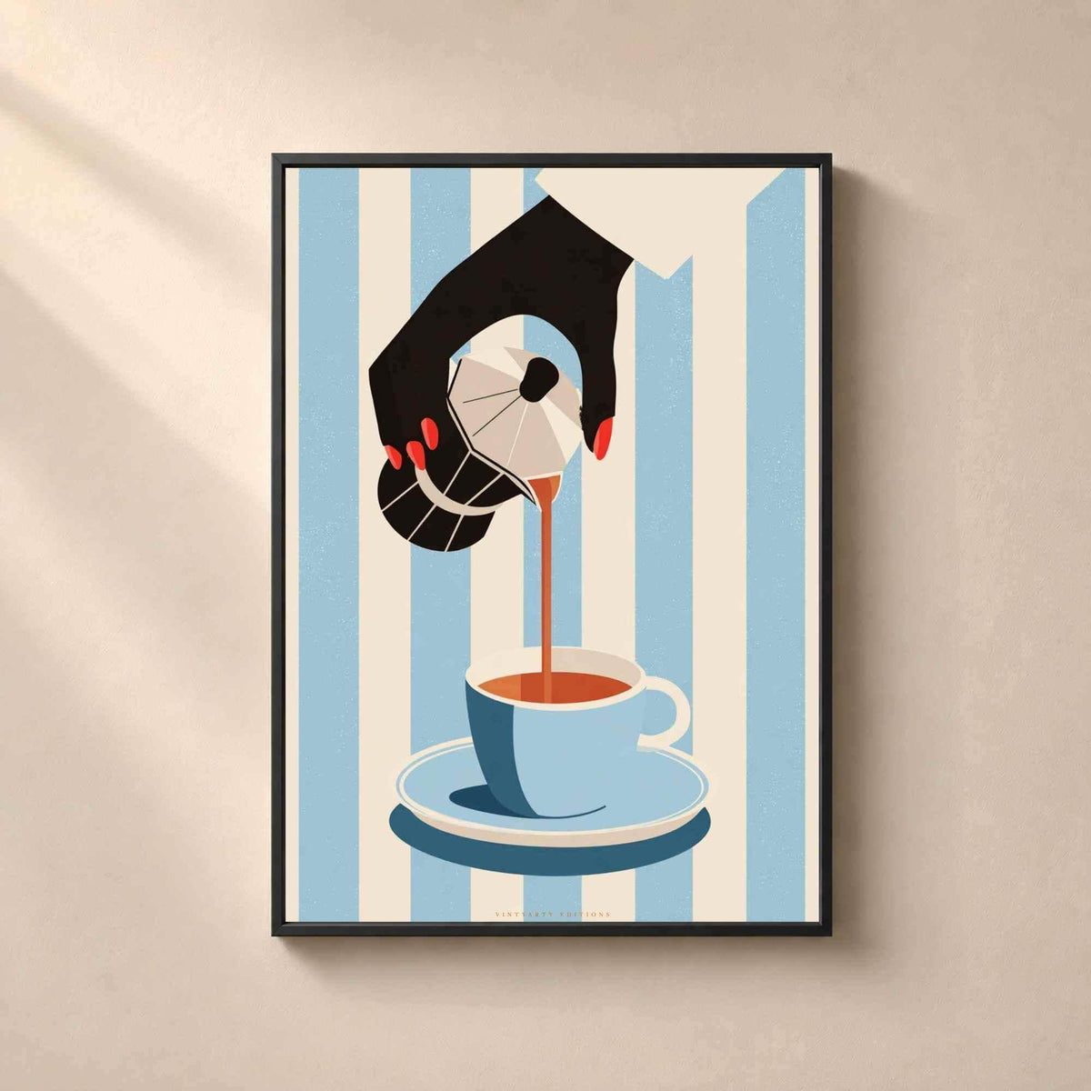 Affiche café dans un cadre en bois noir sur un mur clair, main aux ongles rouges versant un café d'une cafetière moka dans une tasse bleue sur fond rayé.